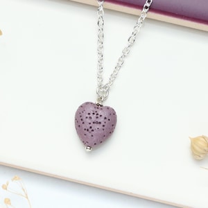 Könnte beinhalten: Eine silberne Kettenkette mit einem violetten herzförmigen Anhänger. Der Anhänger hat eine strukturierte Oberfläche.