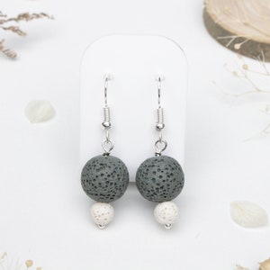 以下が含まれることがあります： グレーの溶岩ビーズと白い溶岩ビーズが付いたイヤリングのペア。イヤリングはシルバーのフックです。