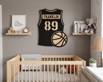 May include: A black and light wood wall decoration shaped like a basketball jersey with the name FRANKLIN and the number 89 printed in a light color. The design includes a basketball graphic on the lower right side of the jersey silhouette.