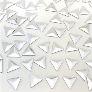 Puede incluir: Una gran cantidad de pedrería plateada en forma de triángulo. La pedrería está esparcida sobre una superficie blanca.