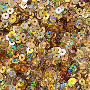 May include: A close-up of a pile of iridescent gold sequins. The sequins are round and have a hole in the center. They are perfect for crafting and decorating.
