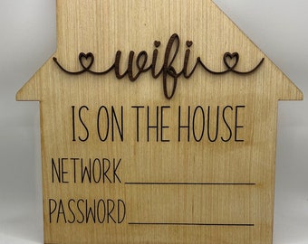 Könnte beinhalten: Hausförmiges Holzschild mit den Worten "wifi IS ON THE HOUSE" in schwarzer Schrift. Das Schild hat Platz, um Netzwerk und Passwort zu schreiben. Das Wort "wifi" ist in Schreibschrift mit Herzakzenten.