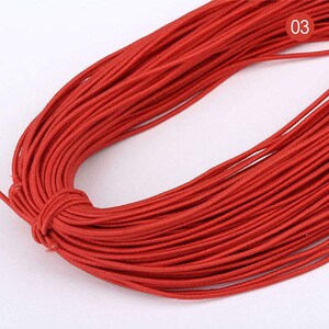 May include: A spool of red elastic string, perfect for crafting projects. The string is wound tightly and appears to be of good quality.