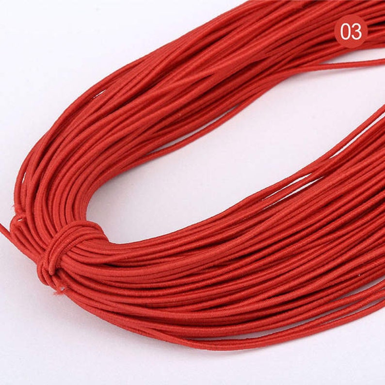 May include: A spool of red elastic string, perfect for crafting projects. The string is wound tightly and appears to be of good quality.
