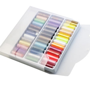 May include: A white plastic storage box with a clear lid, filled with colourful spools of thread. The box has a button closure and is designed to hold and organise sewing thread.