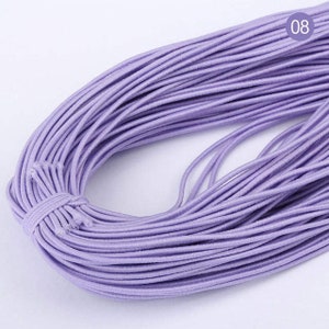May include: A large spool of lavender elastic string. The string is wound tightly and is ready to be used for crafting projects.