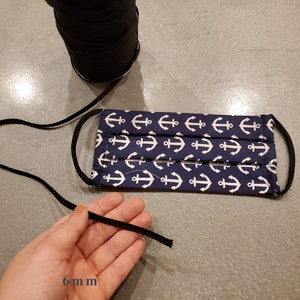 May include: A blue face mask with a white anchor pattern. The mask has black elastic ear loops that are 6 mm wide.