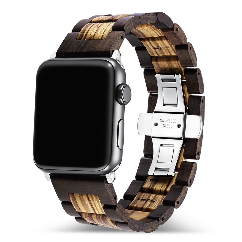 May include: A brown wood and stainless steel Apple Watch band. The band has a dark brown wood finish with light brown wood accents. The band is secured with a stainless steel clasp that says "Stainless Steel".