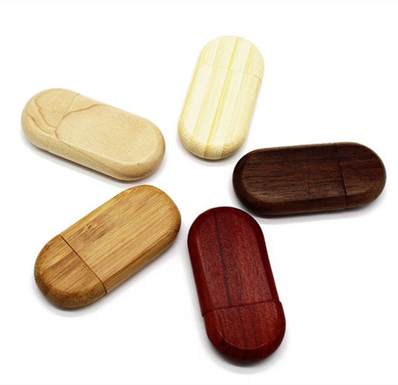 K&ouml;nnte beinhalten: F&uuml;nf USB-Sticks aus Holz in verschiedenen Holzarten: Natur, hellbraun, dunkelbraun und rot. Die Sticks sind oval geformt und haben eine glatte, polierte Oberfl&auml;che.