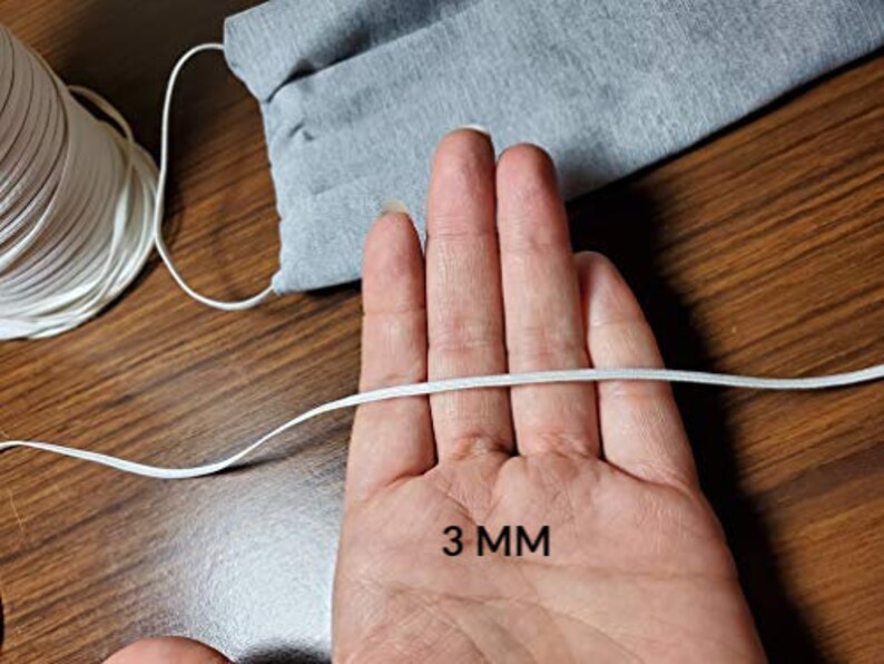 May include: White elastic cord measuring 3 mm in diameter. The cord is held in a hand, with the measurement written below.