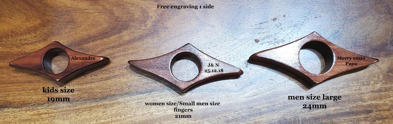 May include: Three wooden bookmark rings in different sizes. The smallest ring is 1.9 inches in diameter, the middle ring is 2.1 inches in diameter, and the largest ring is 2.4 inches in diameter. The rings are engraved with the text "Alexandre", "J&N 25.12.18", and "Merry xmas Papa".