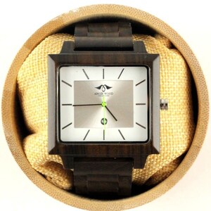 May include: A square-shaped wooden wristwatch with a brown wood band and a white face. The watch face has black hour and minute hands, a green second hand, and the text "Angie Wood Creations" printed on it.