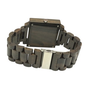 May include: A dark brown wooden wristwatch with a square face and a metal clasp. The watch band is made of linked wooden pieces.