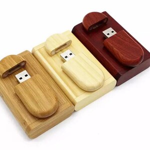 K&ouml;nnte beinhalten: Drei USB-Sticks aus Holz in verschiedenen Farben: Naturholz, helles Holz und dunkelrot. Jeder Stick hat eine Schiebekappe, die den USB-Anschluss freigibt.
