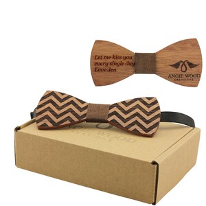 Puede incluir: Una pajarita de madera con un patrón de chevron en marrón y negro. La pajarita viene en una caja de cartón marrón con las palabras "Angie Wood Creations" impresas en ella. La pajarita está grabada con el mensaje "Let me kiss you every single day Love Jen".