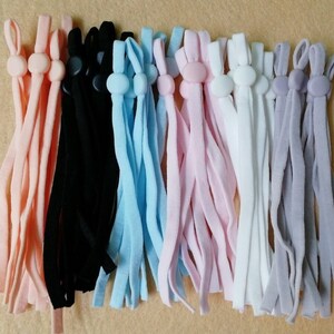 May include: Assortment of 10 pairs of elastic mask strap extenders with adjustable toggles. The extenders are in various colors including peach, black, light blue, pink, white, and gray.