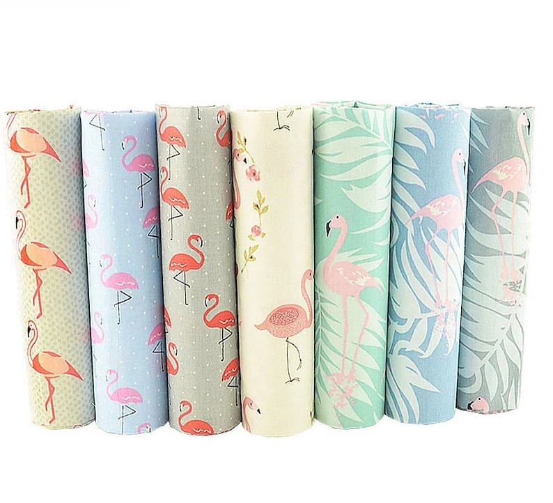 May include: A set of seven fabric panels featuring pink flamingos on various backgrounds. The panels include a light blue background with white polka dots, a gray background with white polka dots, a cream background with pink flowers, a light green background with palm leaves, a light blue background with palm leaves, a gray background with white polka dots, and a light green background with palm leaves.