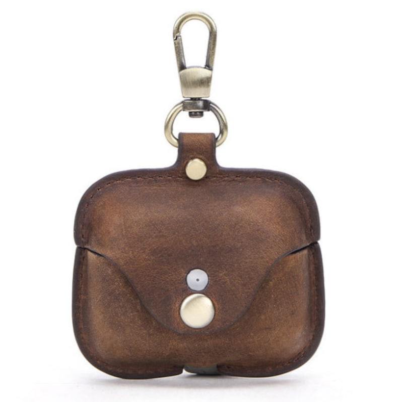 May include: A brown leather case with a gold metal carabiner clip for carrying AirPods. The case has a flap that closes with a snap.