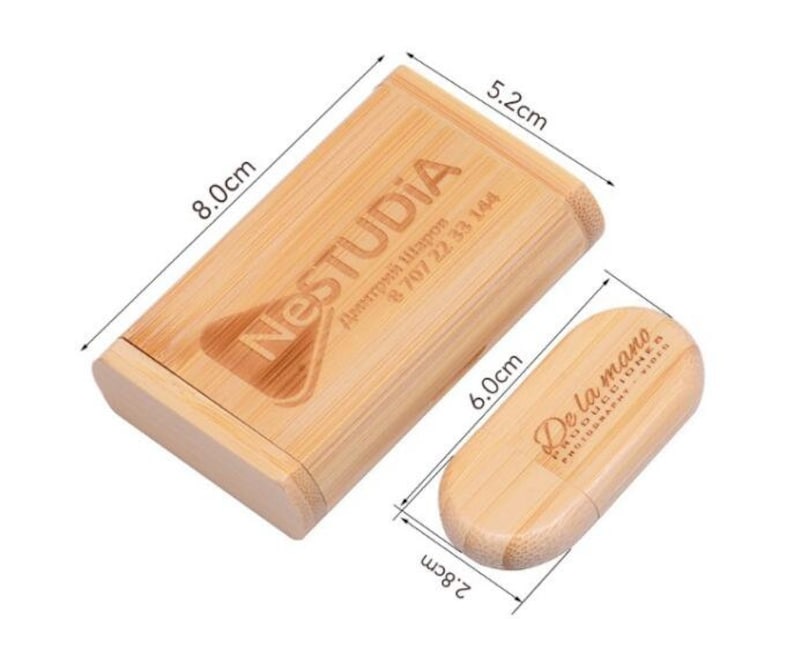 K&ouml;nnte beinhalten: Eine Holzkiste mit Deckel, die 8 cm x 6 cm x 5,2 cm misst, mit dem Text "NESTUDIA" und Kontaktinformationen, die auf der Oberseite eingraviert sind. Die Kiste ist ge&ouml;ffnet und eine kleinere Holzkiste mit dem Text "De la mano" befindet sich im Inneren. Die kleinere Kiste misst 2,8 cm x 6 cm.
