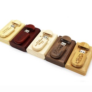 K&ouml;nnte beinhalten: F&uuml;nf USB-Sticks aus Holz mit personalisierten Gravuren. Jeder Stick ist aus einer anderen Holzart und hat eine Schiebekappe, um den USB-Anschluss freizulegen.