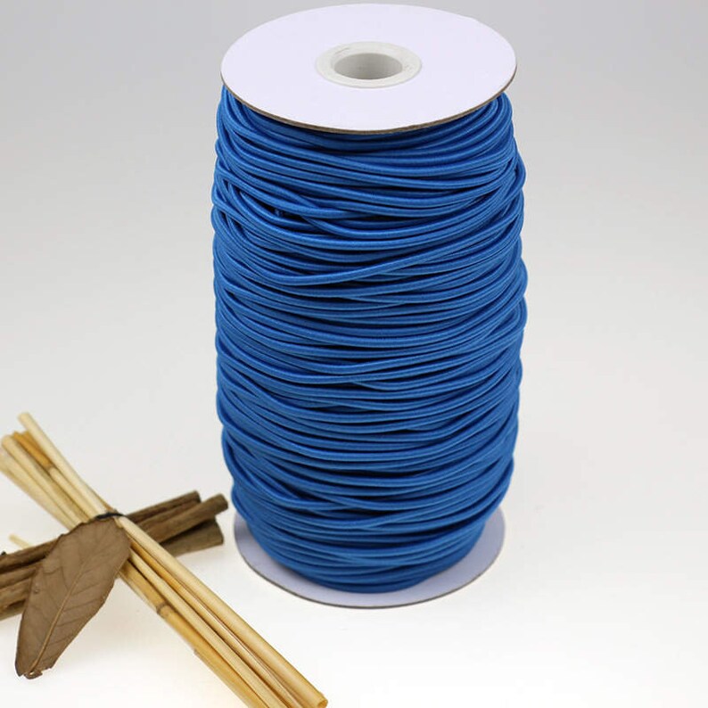 May include: A spool of bright blue elastic cord wound around a white cardboard core. The elastic cord is used for crafts, sewing, and jewelry making.
