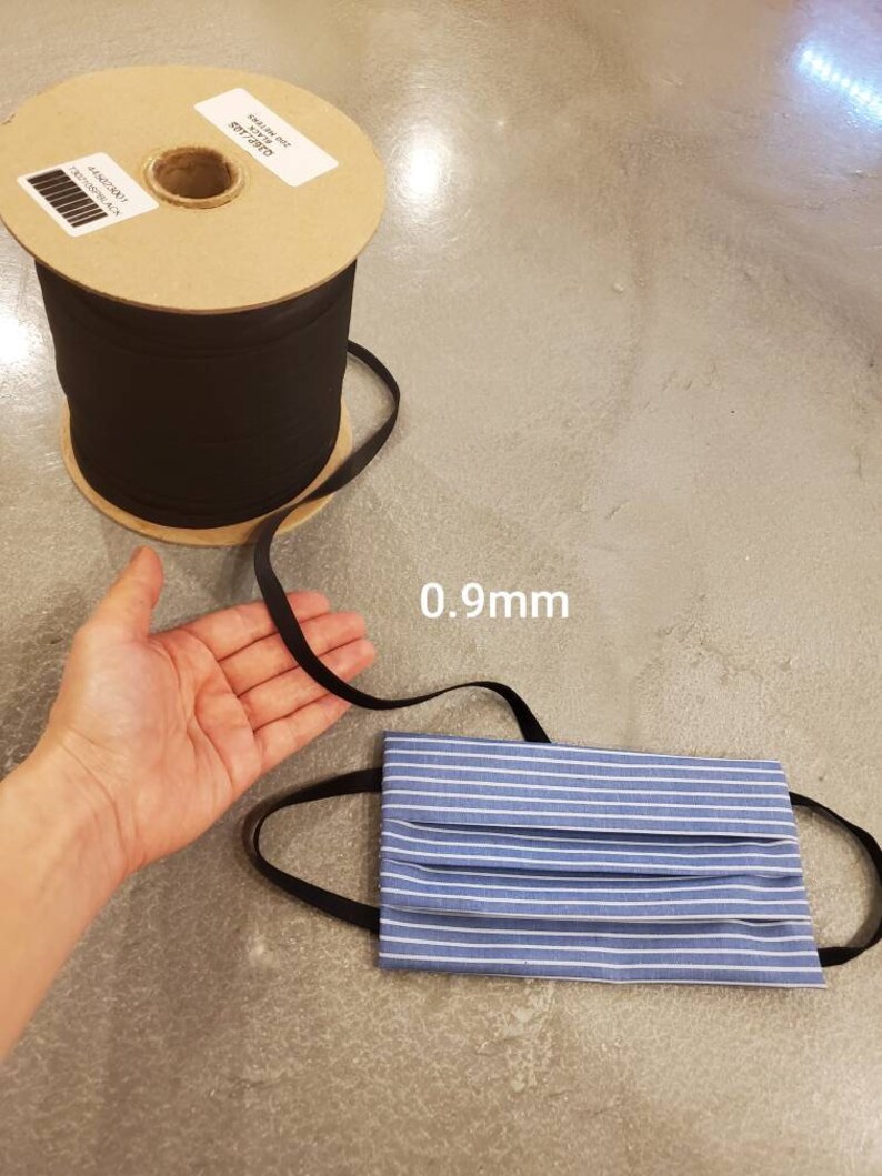 May include: A spool of black elastic cord with a label that reads "0.9mm" and a blue and white striped fabric face mask with black elastic straps.