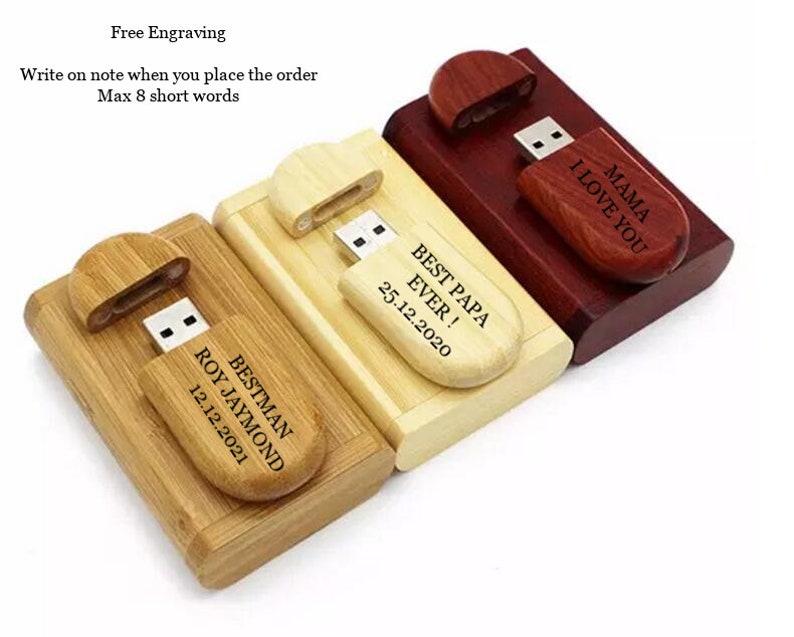 K&ouml;nnte beinhalten: Drei Holz-USB-Sticks mit personalisierten Gravuren. Die Sticks sind in Naturholz, Dunkelholz und Hellholz. Die Gravuren beinhalten "Bestman Roy Jaymond 12.12.2021", "Best Papa Ever! 25.12.2020" und "Mama I Love You".