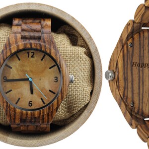 May include: A wooden wristwatch with a brown wood band and a brown face with black hands and numbers. The back of the watch has an inscription that reads "Happy 5th Sean. Love, Katie."