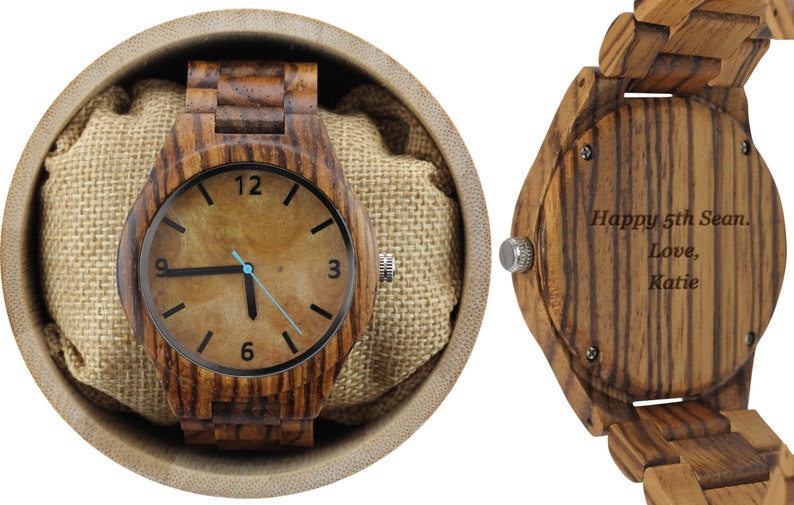 May include: A wooden wristwatch with a brown wood band and a brown face with black hands and numbers. The back of the watch has an inscription that reads "Happy 5th Sean. Love, Katie."