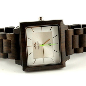 May include: A square-shaped wooden wristwatch with a brown wooden band. The watch face is white with black markings and the text "AMARE WOOD" in the center.