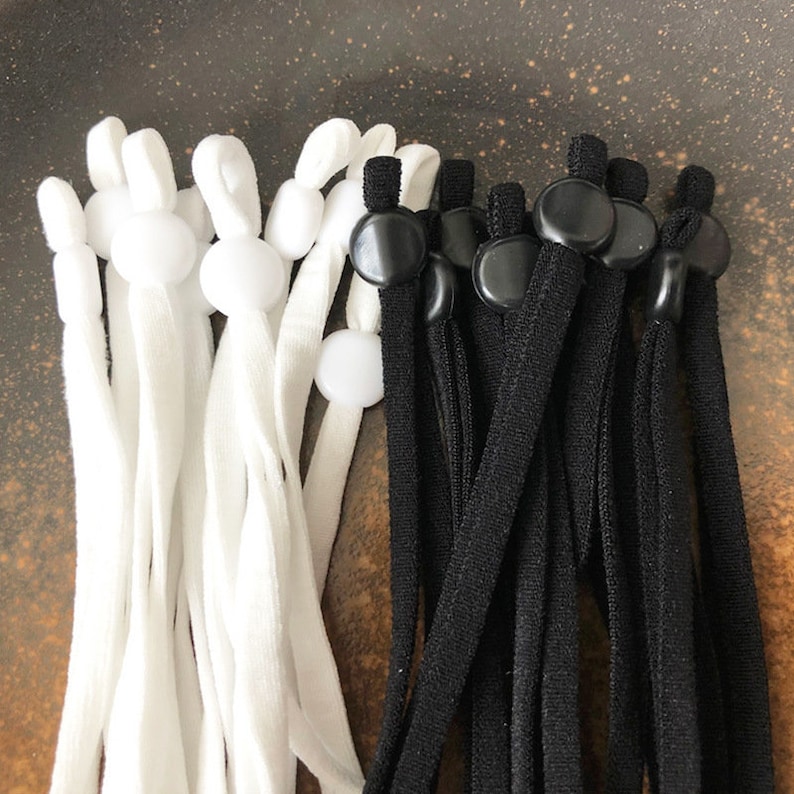 May include: A set of white and black elastic mask strap extenders with adjustable toggles. The extenders are made of a soft, stretchy material and have a comfortable fit.