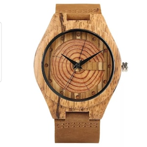 May include: A wooden wristwatch with a brown leather strap. The watch face features a circular design with concentric rings of wood.