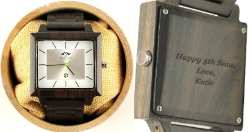 May include: A square wooden watch with a silver face and black hands. The watch is in a box with a brown fabric lining. The back of the watch has an engraved message that reads "Happy 5th Sean. Love, Katie."