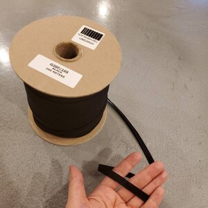 May include: A spool of black elastic cord with a label that reads "Q36P/10S BLACK 200 METERS".