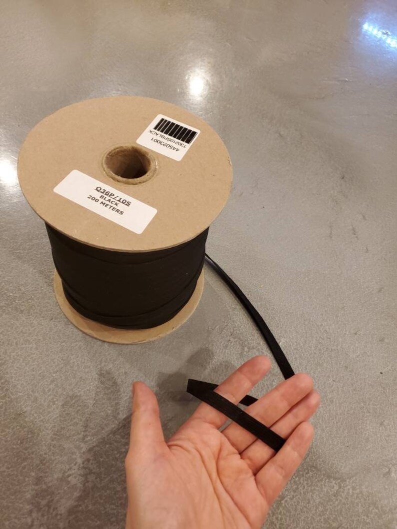 May include: A spool of black elastic cord with a label that reads "Q36P/10S BLACK 200 METERS".