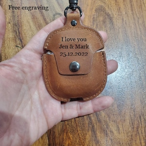 May include: Brown leather Airpods case with a black metal carabiner clip. The case has the text "I love you Jen & Mark 25.12.2022" engraved on it.