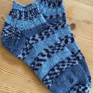 May include: A pair of blue and white patterned ankle socks. The socks are knitted and have a geometric design.