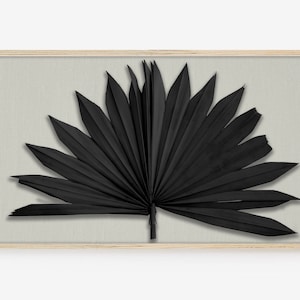 Puede incluir: Impresión artística enmarcada de una hoja de palma negra sobre un fondo gris claro. La hoja está extendida, con un marco de madera natural. La obra tiene una estética minimalista y moderna, ideal para decoración.
