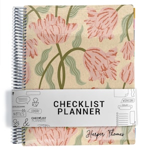 May include: A spiral-bound planner featuring a beige cover with a pink and green tulip floral pattern. A white paper band wraps around the center with the text "CHECKLIST PLANNER" and "Harper Thomas" printed on the cover below the band.