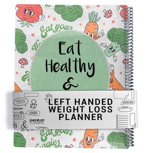 May include: A spiral-bound planner with a cover featuring cartoon vegetables and the text "Eat Healthy & Left Handed Weight Loss Planner." The design includes carrots, broccoli, and the words "Eat your veggies."