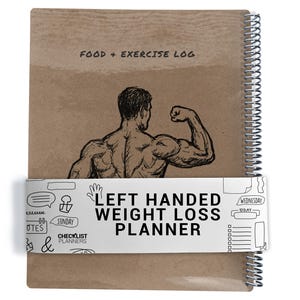 May include: A spiral-bound weight loss planner with a kraft paper cover. The cover features a sketch of a flexing bodybuilder and the text "FOOD + EXERCISE LOG." A white band across the planner reads "LEFT HANDED WEIGHT LOSS PLANNER."