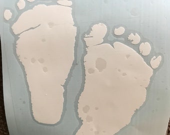 Peut inclure: Deux empreintes de pieds de bébé blanches sur un fond bleu clair.