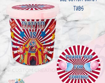 May include: A 20oz clear plastic tub of cotton candy with a carnival-themed label featuring red and white stripes, a yellow tent, clowns, and the text David is 2. A matching round sticker displays the text Thank You For Coming with cotton candy.