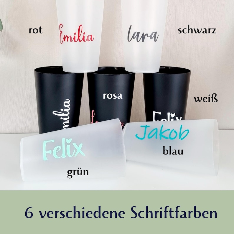 May include: A collection of personalized cups in various colors. The cups are white and black, with names written in red, black, and blue. The text "6 verschiedene Schriftfarben" is at the bottom.