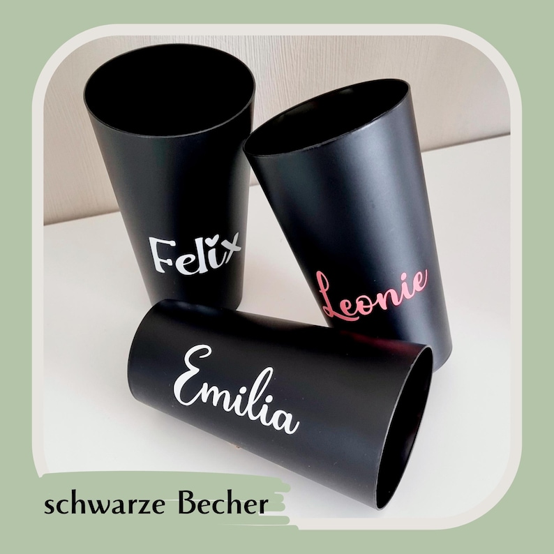 May include: Three black cylindrical tumblers with personalized names in white and pink. The names "Felix", "Leonie", and "Emilia" are displayed on the tumblers. The phrase "schwarze Becher" is at the bottom.