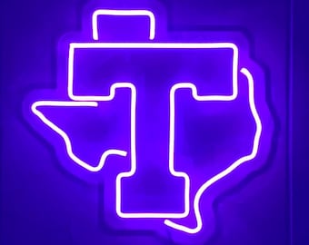May include: A white neon sign shaped like the state of Texas with a large "T" in the centre. The sign is lit up in a bright purple colour.