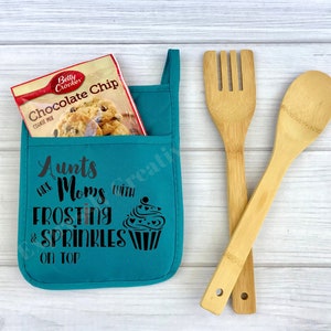 May include: Teal oven mitt with a pocket that holds a box of chocolate chip cookie mix. The oven mitt has the text "Aunts are Moms with Frosting & Sprinkles on Top" and a cupcake graphic.