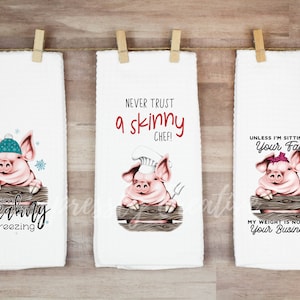 May include: Three white kitchen towels with pig illustrations and humorous text. One pig wears a hat and says "I am freaking freezing." Another pig, wearing a chef's hat, says "Never trust a skinny chef!" The third pig says "Unless I'm sitting on your face."