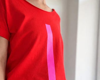 Feminine oversize shirt with wide neckline and fluorescent pink print – bold, relaxed, artistic and effortlessly unique