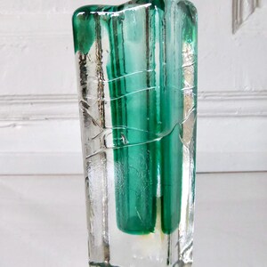 May include: A rectangular glass vase with a clear exterior and a vibrant green interior. The vase has a textured, cracked appearance on the outside, with vertical green stripes visible through the clear glass. The vase is a decorative item.